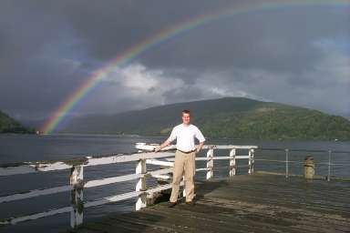 Picture of Armin standing on a pier under a rainbow