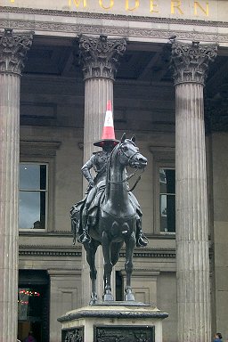 Picture of a statue with a traffic cone on its head, outside of the Gallery of Modern Art