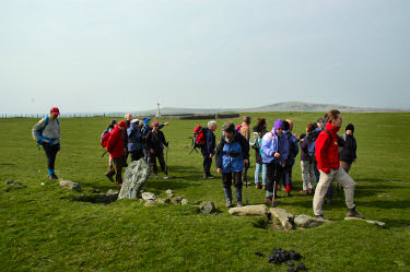 Picture of walkers near the cross-slab, Kilchoman Military Cemetery in the background