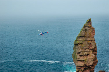 Picture of a low flying helicopter near a rock stack