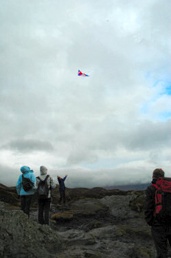 Picture of people flying a kite on the top of a mountain