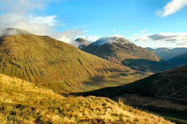 Picture of a view over a glen with various mountains in the background