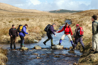 Picture of walkers using stepping stones to cross a burn