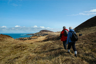 Picture of two walkers approaching a hill near the sea