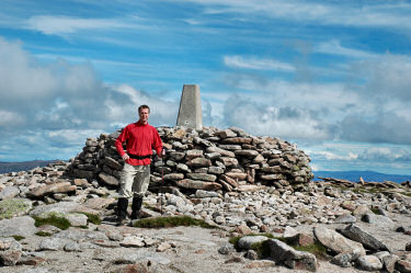 Picture of a walker standing in front of a summit cairn