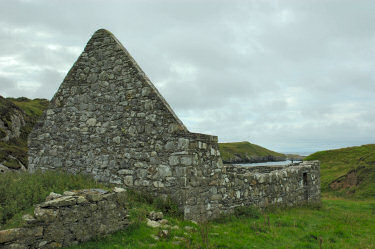 Picture of a view of the ruins of a chapel (Kilchiaran) with a bay in the background