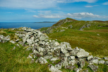 Picture of the remains of a stone wall of a dun (Dun Bhoraraig), wild landscape in the background