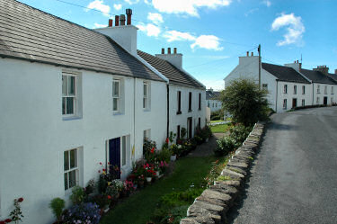 Picture of a view along a street with whitewashed houses and 'sunk gardens' in Port Charlotte, Islay