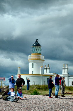 Picture of a lighthouse with people sitting in front it