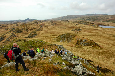 Picture of walkers going down a hill with interesting rock formations in the background