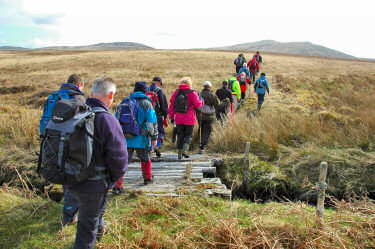 Picture of a group of walkers crossing a bridge over a burn (stream)