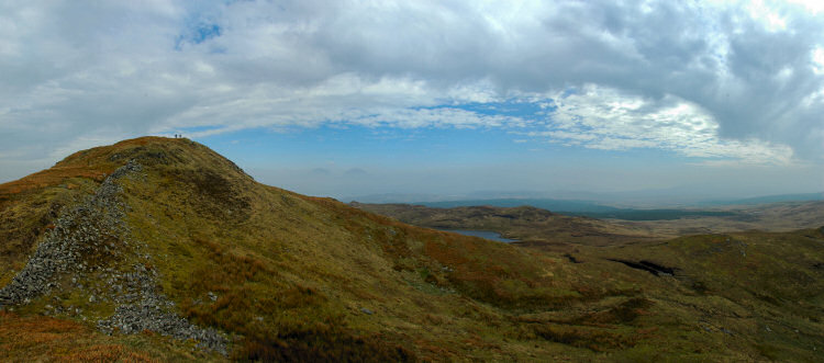 Picture of a panoramic view over a hill, two other hill tops just visible in the distance over an inversion