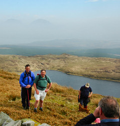 Picture of two walkers standing on the top of a hill, a third one taking a picture