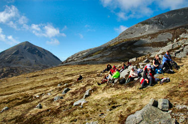 Picture of a group of walkers resting for lunch under two mountains