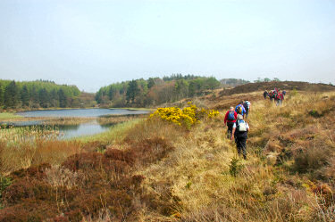 Picture of walkers walking along a beautiful loch/lake (Lily Loch on Islay)