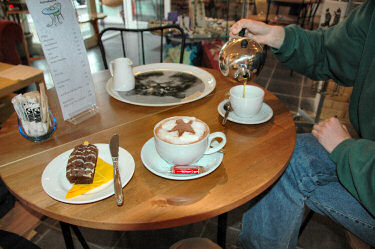 Picture of a cup of hot chocolate, some chocolate cake and a tea being poured
