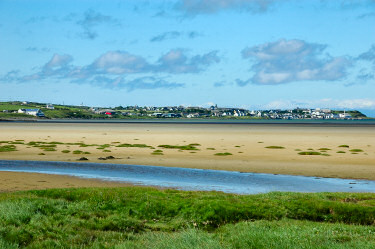 Picture of a coastal village seen across a beachy shore at low tide