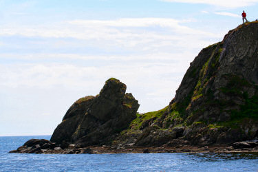 Picture of a man standing on a small rocky hill over a bay