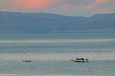 Picture of a skiff being rowed, followed by a RIB