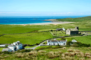 Picture of a large house, a row of cottages and the ruin of a church with a beach in the background