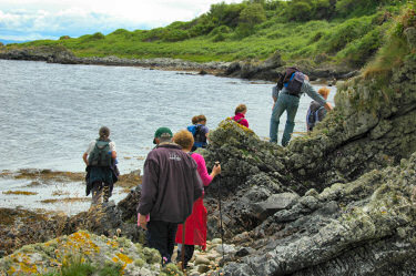 Picture of a group of walkers scrambling over some rocks along the sea