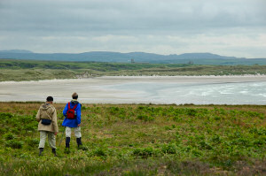 Picture of a couple approaching a beach across some rough landscape