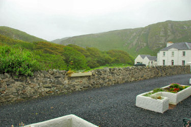 Picture of grey skies over a house in front of some crags