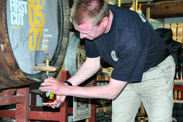 Picture of a man filling a bottle of whisky from a cask