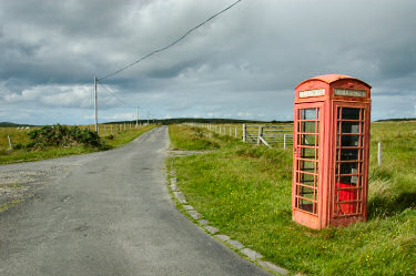 Picture of an old style red phone box at a single track road