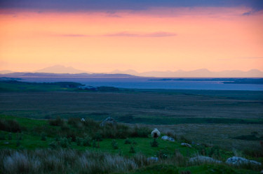 Picture of a colourful sky over a sea loch at sunset, mountains in the background