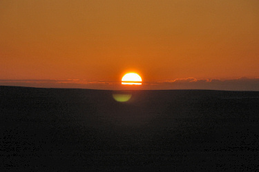 Picture of the sun disappearing behind some hills
