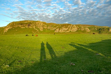 Picture of a view to some crags over a field in the late evening lights